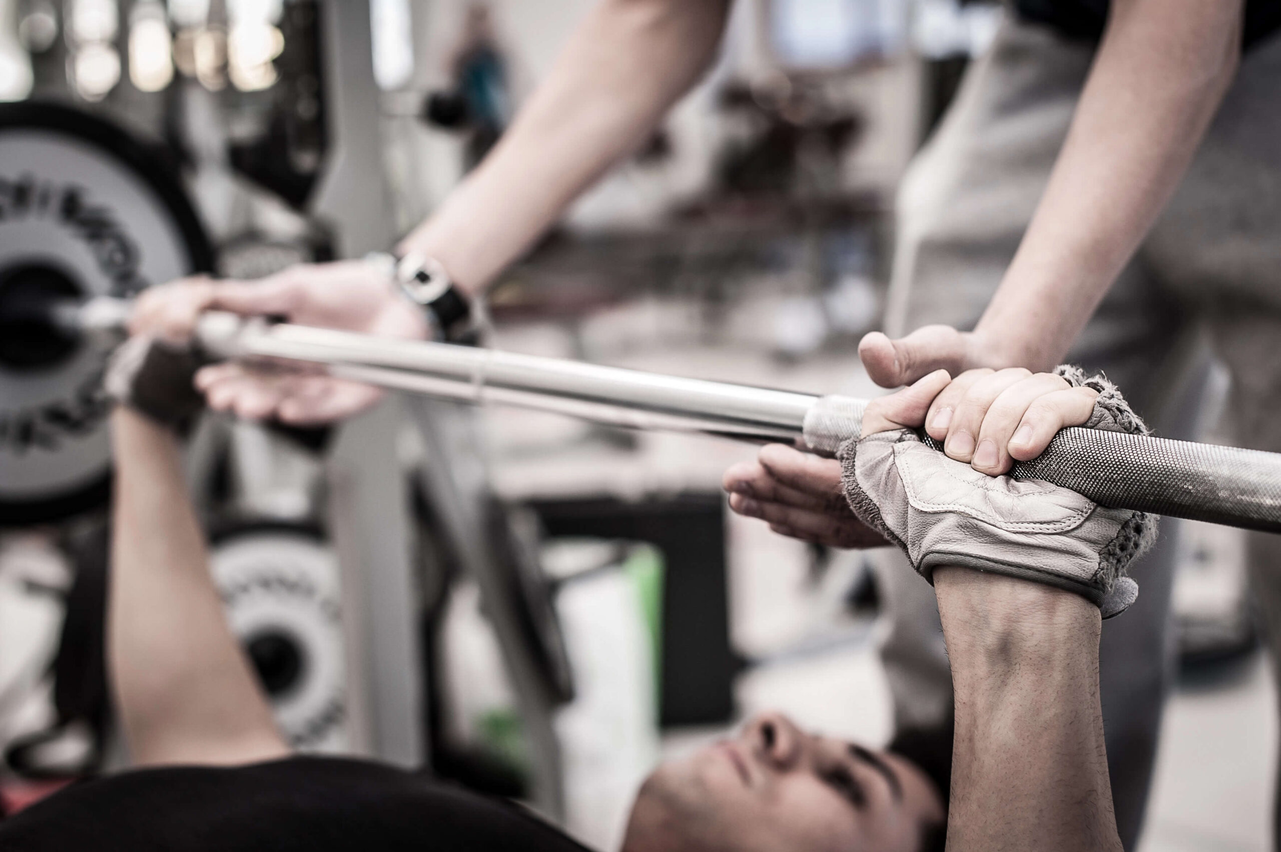 Athlete performing a barbell bench press with a spotter during strength training | Castine Concierge Physical Therapy | Mobile Physical Therapy Services Washington DC